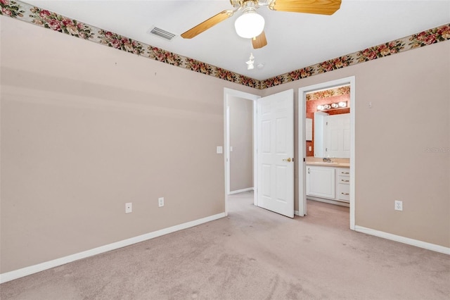 unfurnished bedroom featuring sink, connected bathroom, ceiling fan, and light colored carpet