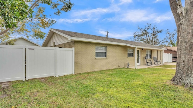 back of property featuring a patio area and a lawn