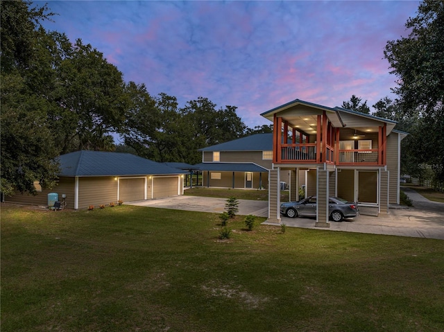 back house at dusk featuring a garage, a sunroom, an outbuilding, and a yard