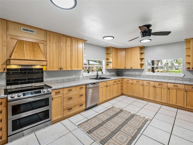 kitchen featuring stainless steel appliances, plenty of natural light, tile counters, and custom range hood