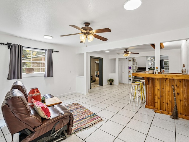 tiled living room featuring ceiling fan and a textured ceiling