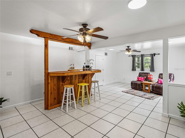 kitchen with a textured ceiling, ceiling fan, a breakfast bar, and beamed ceiling