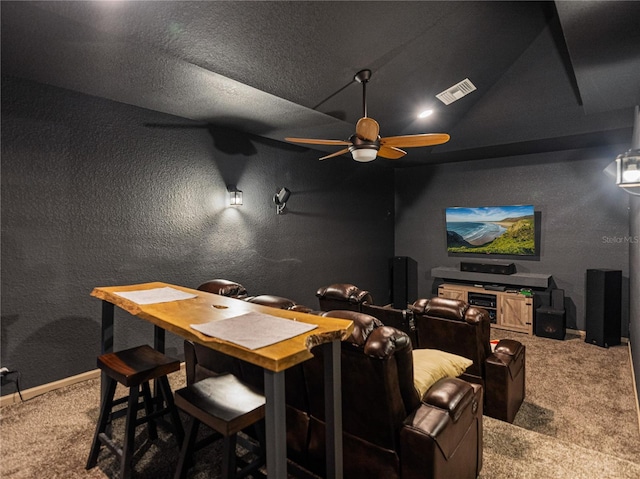 carpeted home theater with vaulted ceiling, ceiling fan, and a textured ceiling