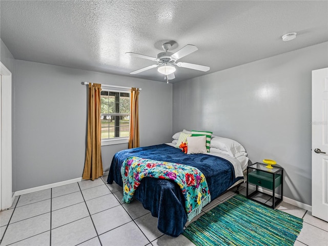 bedroom featuring ceiling fan, light tile patterned flooring, and a textured ceiling