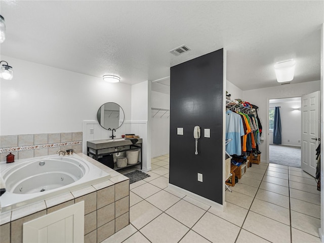 bathroom featuring sink, a textured ceiling, tiled tub, and tile patterned flooring