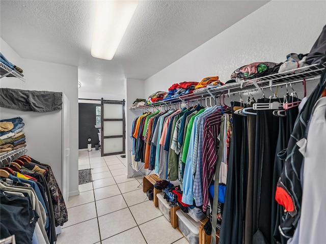 walk in closet featuring a barn door and light tile patterned flooring