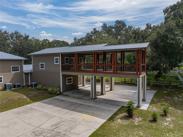 view of front of home featuring a sunroom, a carport, and central AC