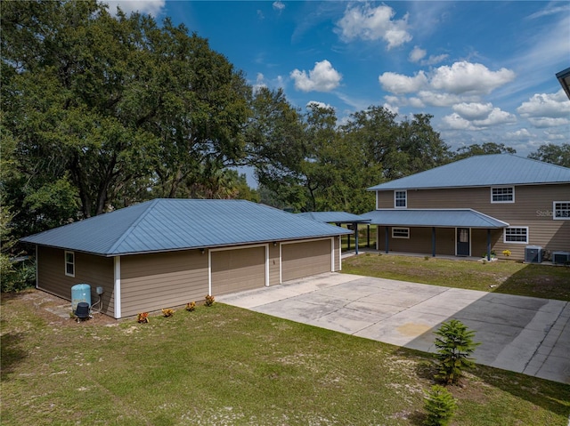 garage featuring central AC unit, a carport, and a yard