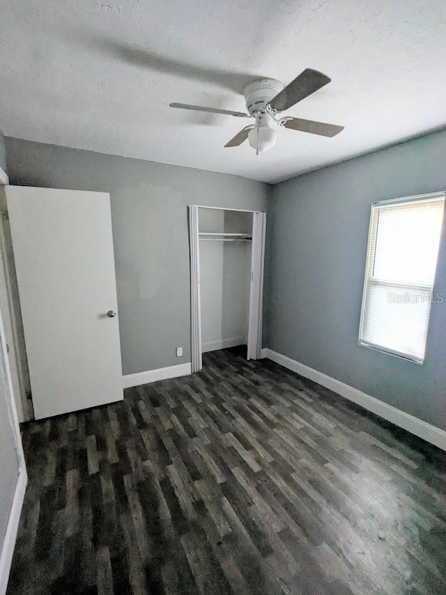 unfurnished bedroom featuring dark wood-type flooring, a textured ceiling, ceiling fan, and a closet