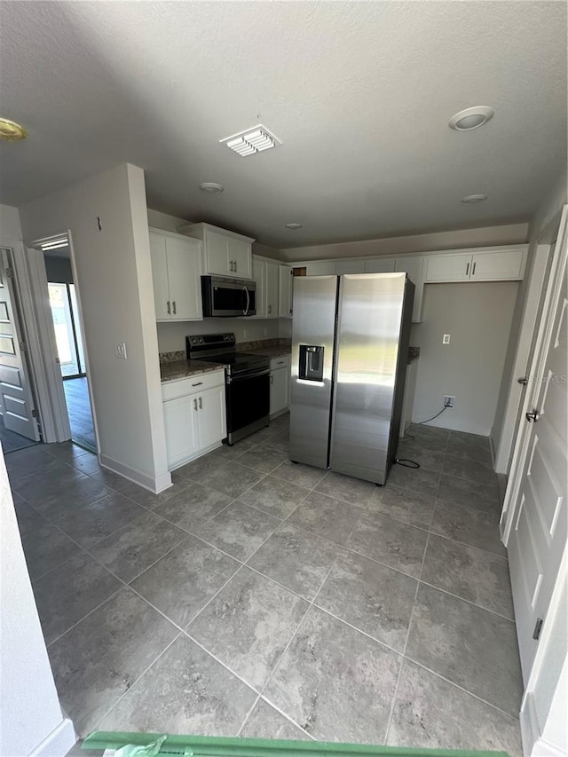 kitchen featuring appliances with stainless steel finishes, white cabinetry, visible vents, and a textured ceiling