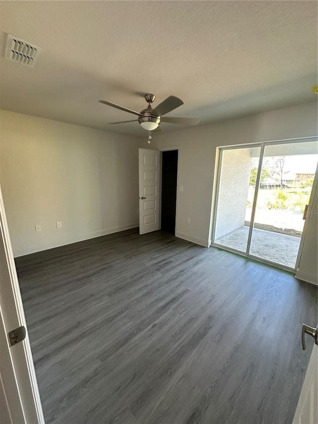 empty room featuring baseboards, visible vents, a ceiling fan, dark wood-type flooring, and a textured ceiling