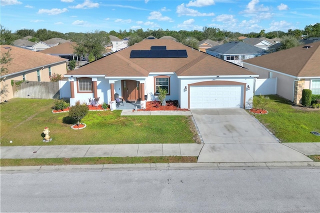 view of front facade with a front yard, a garage, and solar panels