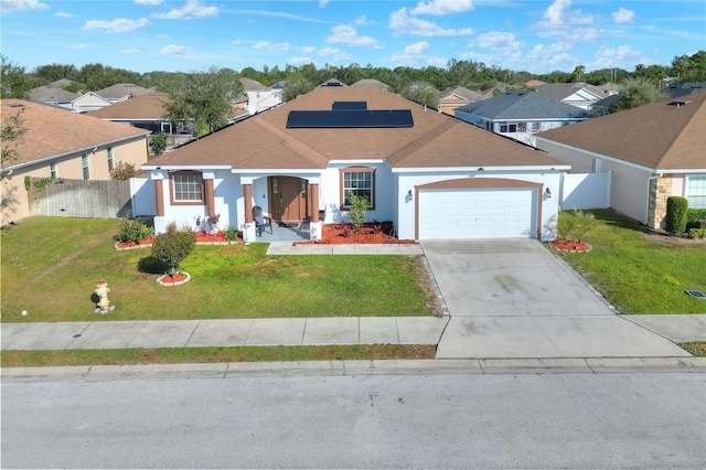 view of front of home with roof mounted solar panels, fence, a front lawn, and a residential view