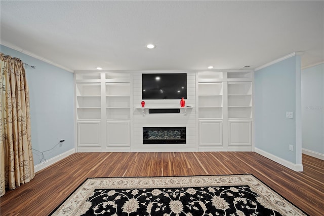 unfurnished living room featuring built in shelves, a large fireplace, ornamental molding, and dark hardwood / wood-style floors