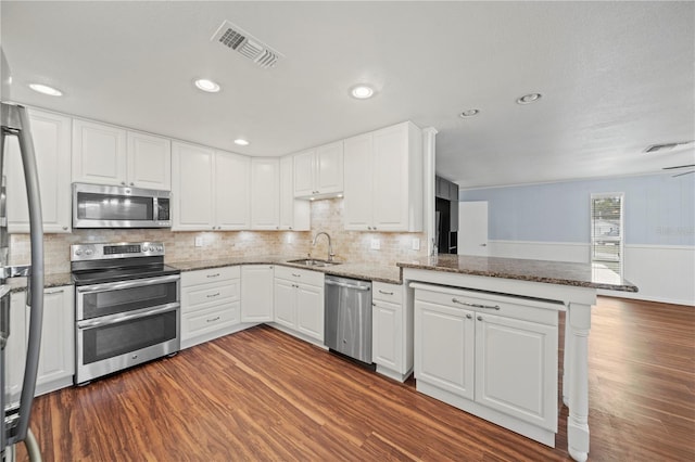 kitchen featuring white cabinetry, kitchen peninsula, stainless steel appliances, dark wood-type flooring, and sink