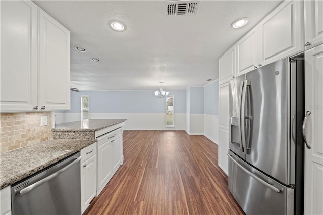 kitchen with light stone countertops, pendant lighting, stainless steel appliances, and white cabinetry