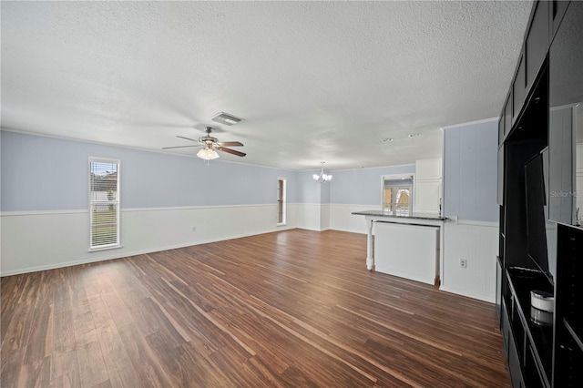 unfurnished living room featuring ceiling fan with notable chandelier, dark wood-type flooring, and a textured ceiling