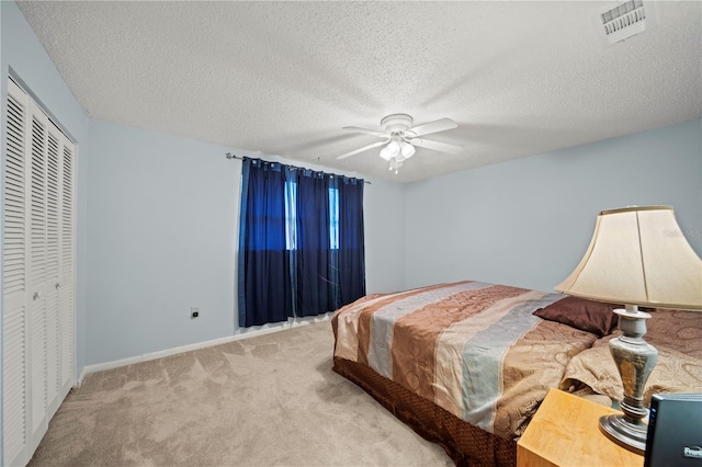 carpeted bedroom featuring ceiling fan, a closet, and a textured ceiling