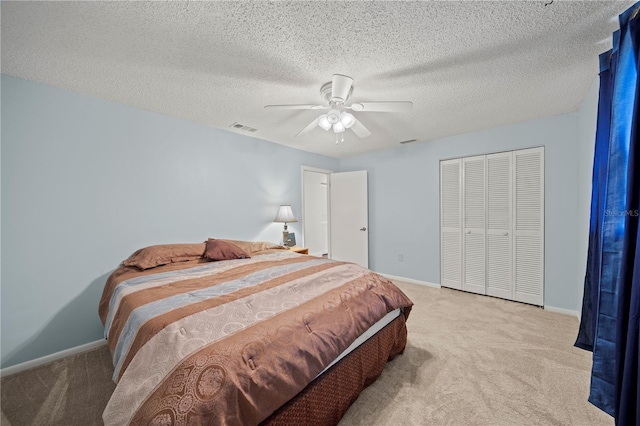 carpeted bedroom with ceiling fan, a textured ceiling, and a closet