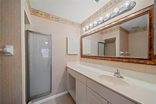 bathroom featuring an enclosed shower, vanity, tile patterned floors, and a textured ceiling