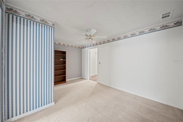 spare room featuring ceiling fan, light colored carpet, and a textured ceiling