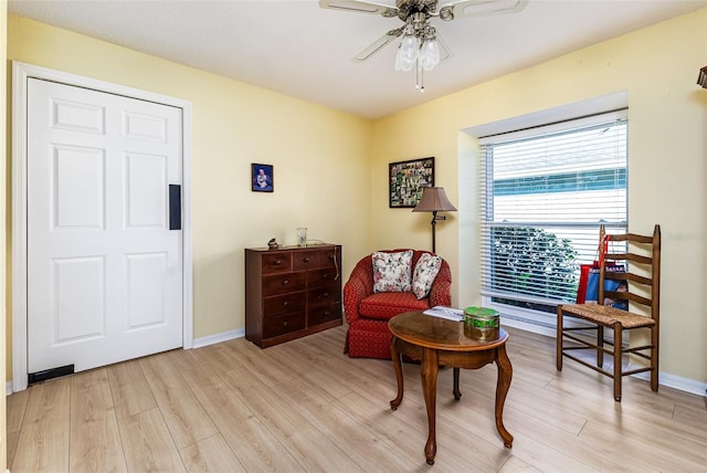 living area featuring baseboards, light wood-style floors, and ceiling fan