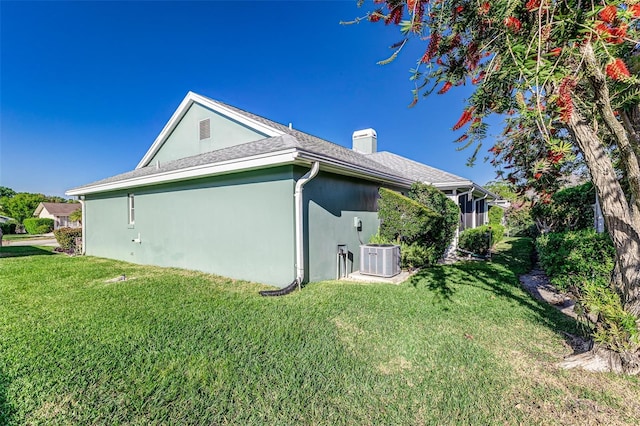 view of home's exterior featuring stucco siding, a lawn, central AC, and a chimney