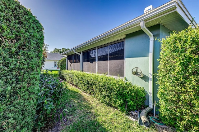 view of side of property featuring a sunroom and stucco siding