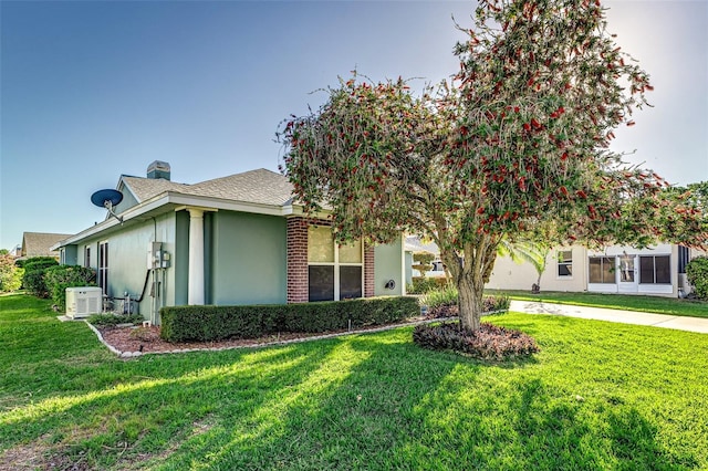 view of front of house featuring a front lawn, a chimney, roof with shingles, and stucco siding