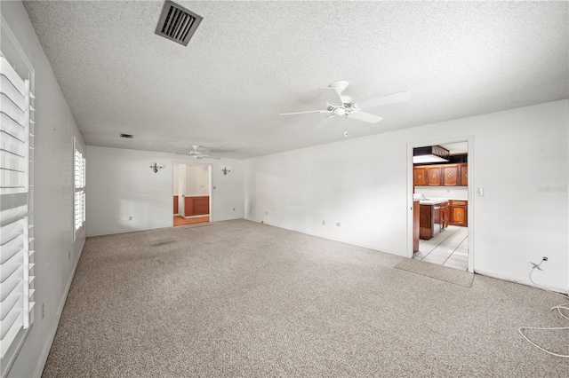 unfurnished room featuring ceiling fan, light colored carpet, and a textured ceiling