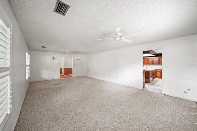 carpeted spare room with ceiling fan and a textured ceiling