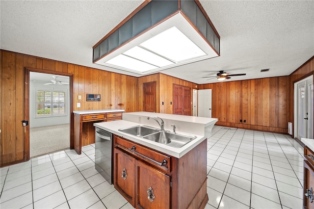 kitchen with light tile patterned floors, sink, stainless steel dishwasher, and a center island with sink