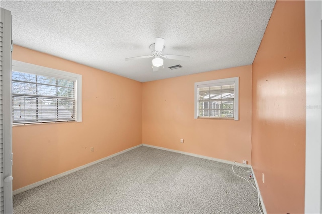 carpeted spare room featuring a textured ceiling and ceiling fan