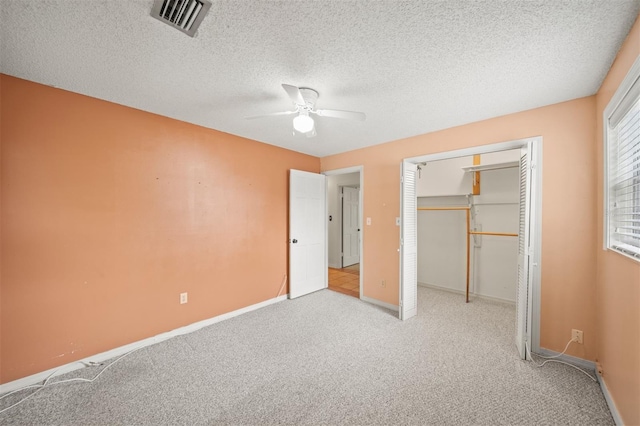 unfurnished bedroom with ceiling fan, light colored carpet, a textured ceiling, and a closet