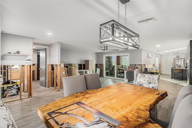 dining area featuring ceiling fan with notable chandelier and light hardwood / wood-style flooring