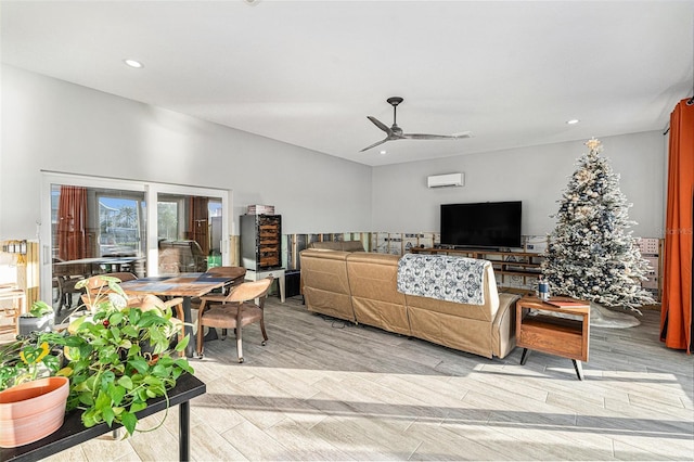 living room with ceiling fan, a wall mounted air conditioner, and light hardwood / wood-style floors