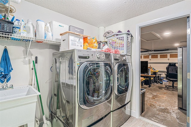 clothes washing area featuring washing machine and dryer, a textured ceiling, and sink