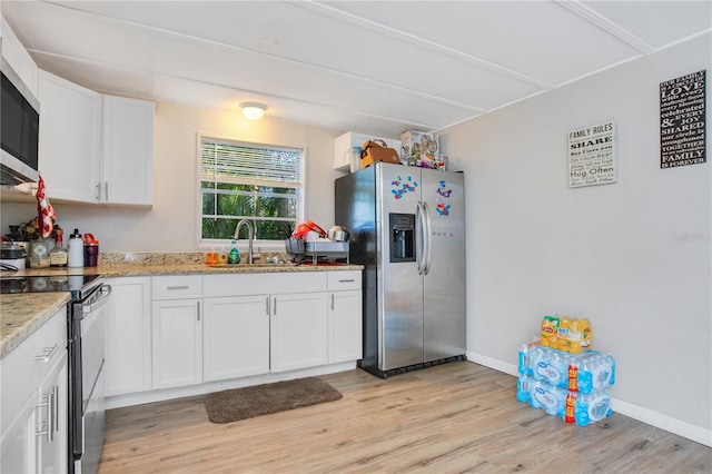 kitchen featuring light stone counters, light hardwood / wood-style flooring, stainless steel appliances, white cabinets, and sink