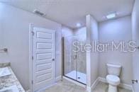 bathroom featuring toilet, vanity, and a shower with shower door