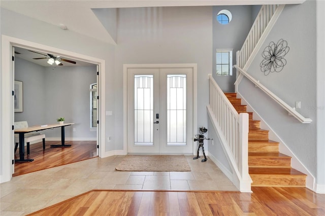 foyer with a towering ceiling, light wood-type flooring, and french doors