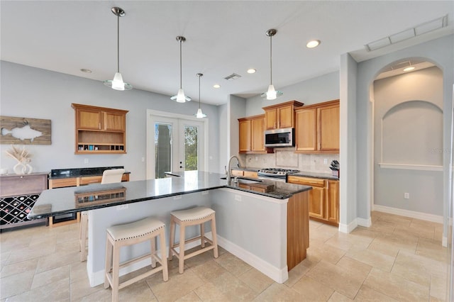 kitchen with sink, tasteful backsplash, hanging light fixtures, stainless steel appliances, and a large island