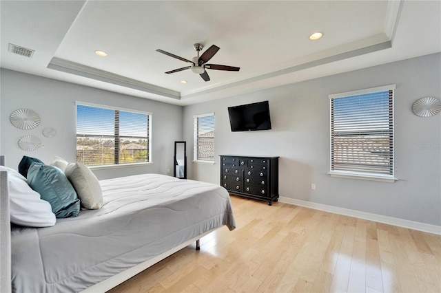 bedroom featuring ceiling fan, a raised ceiling, and light hardwood / wood-style floors