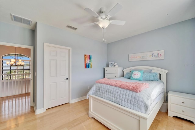 bedroom featuring ceiling fan with notable chandelier and light hardwood / wood-style floors