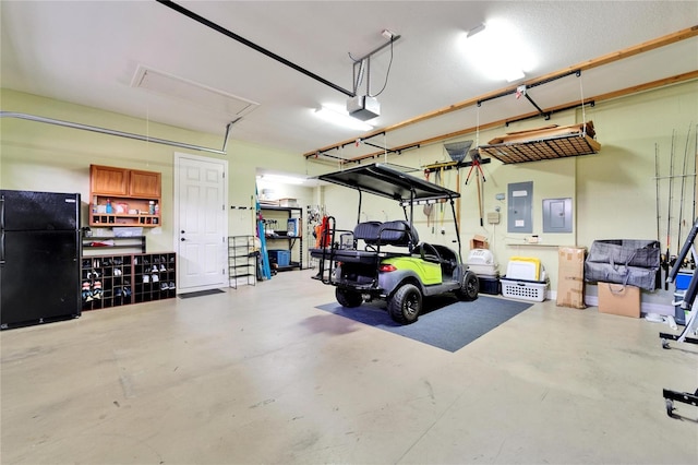 garage with a garage door opener, black fridge, and electric panel