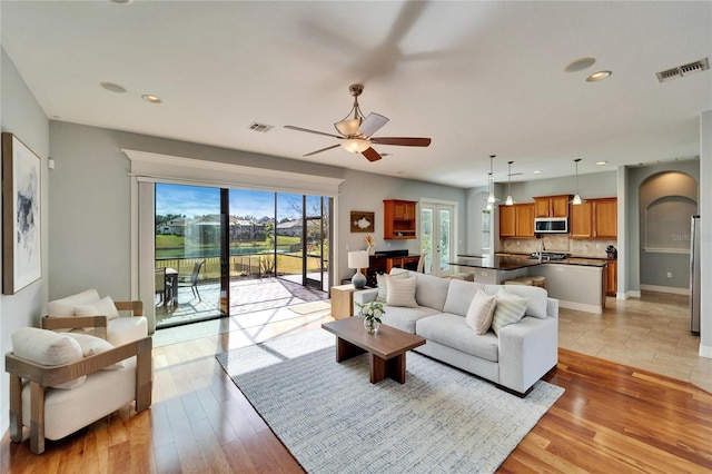 living room with plenty of natural light, light hardwood / wood-style floors, and ceiling fan