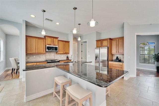 kitchen featuring stainless steel appliances, a breakfast bar, pendant lighting, and a spacious island