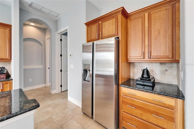 kitchen with tasteful backsplash, stainless steel fridge with ice dispenser, and dark stone counters