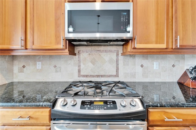 kitchen with tasteful backsplash, stainless steel appliances, and dark stone countertops