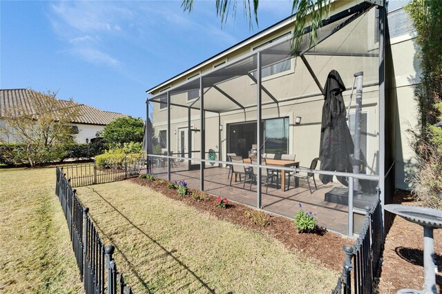 rear view of house with a patio, a yard, and glass enclosure