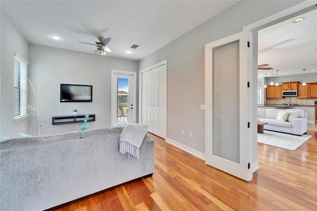 living room featuring ceiling fan and light hardwood / wood-style floors